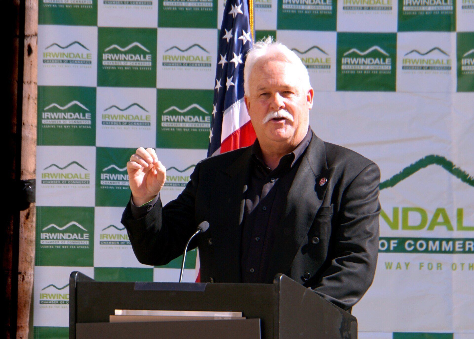 A man stands at a podium with an american flag behind him