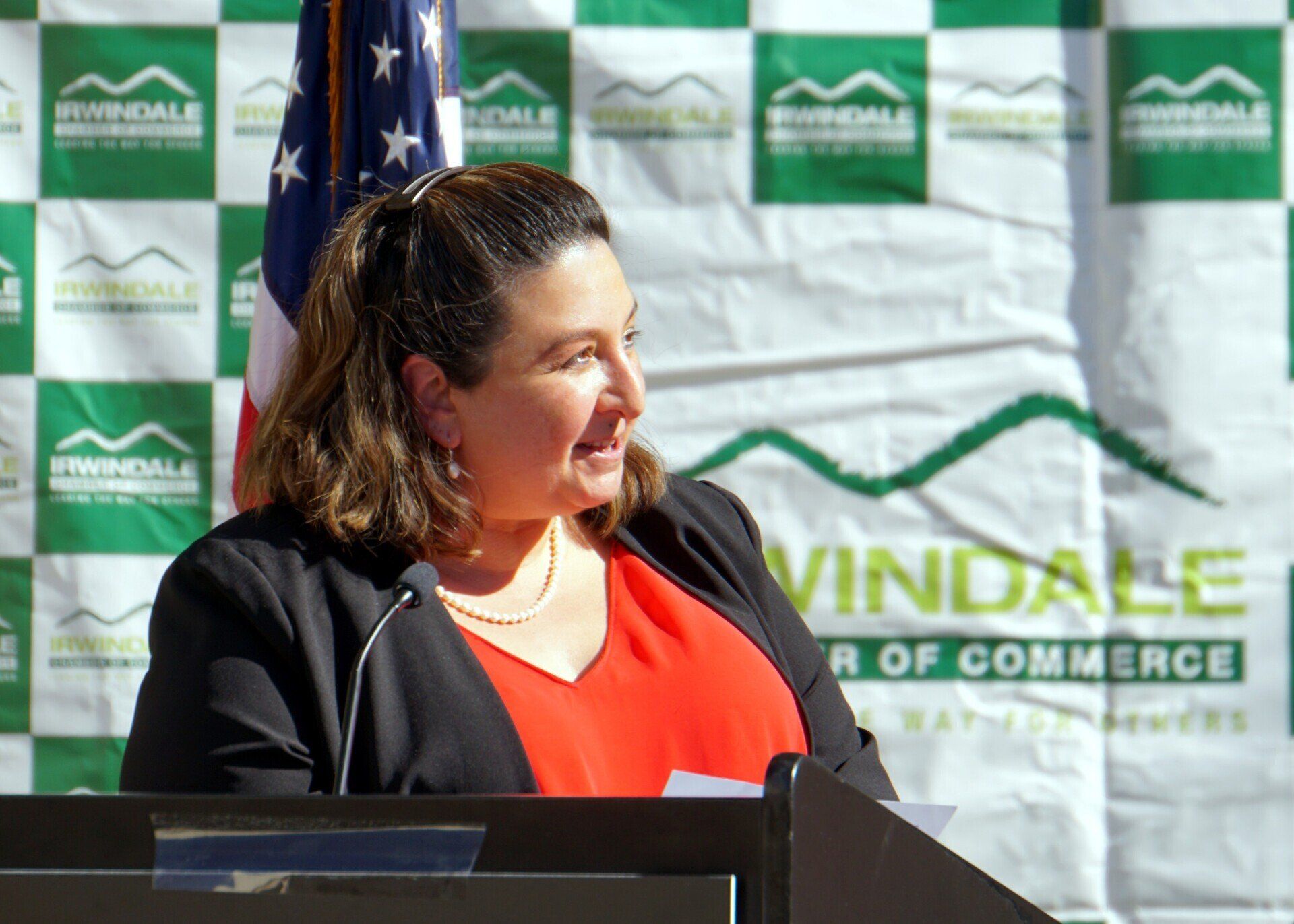 A woman stands at a podium in front of a winddale banner