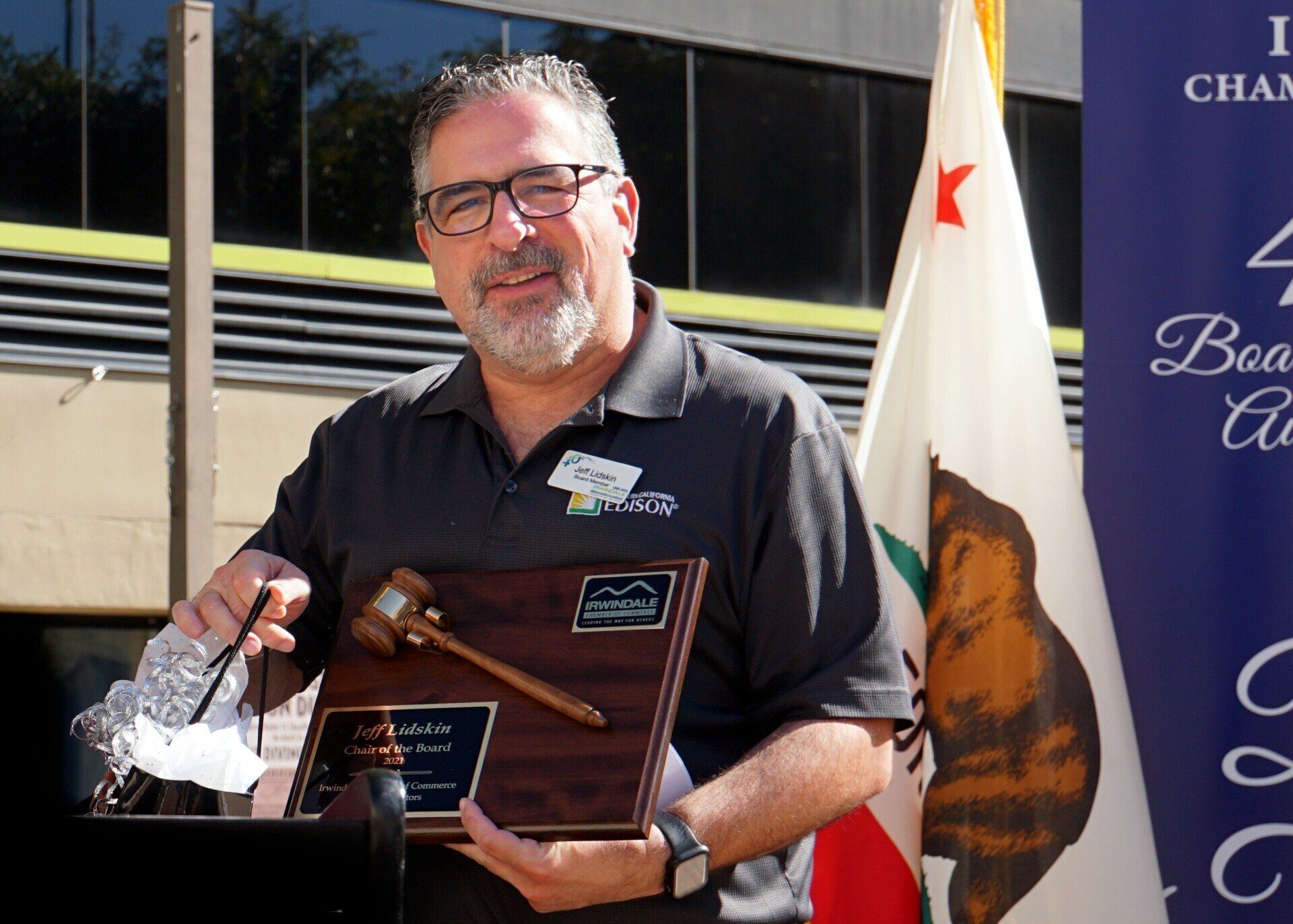 A man holding a plaque and a gavel in front of a california flag