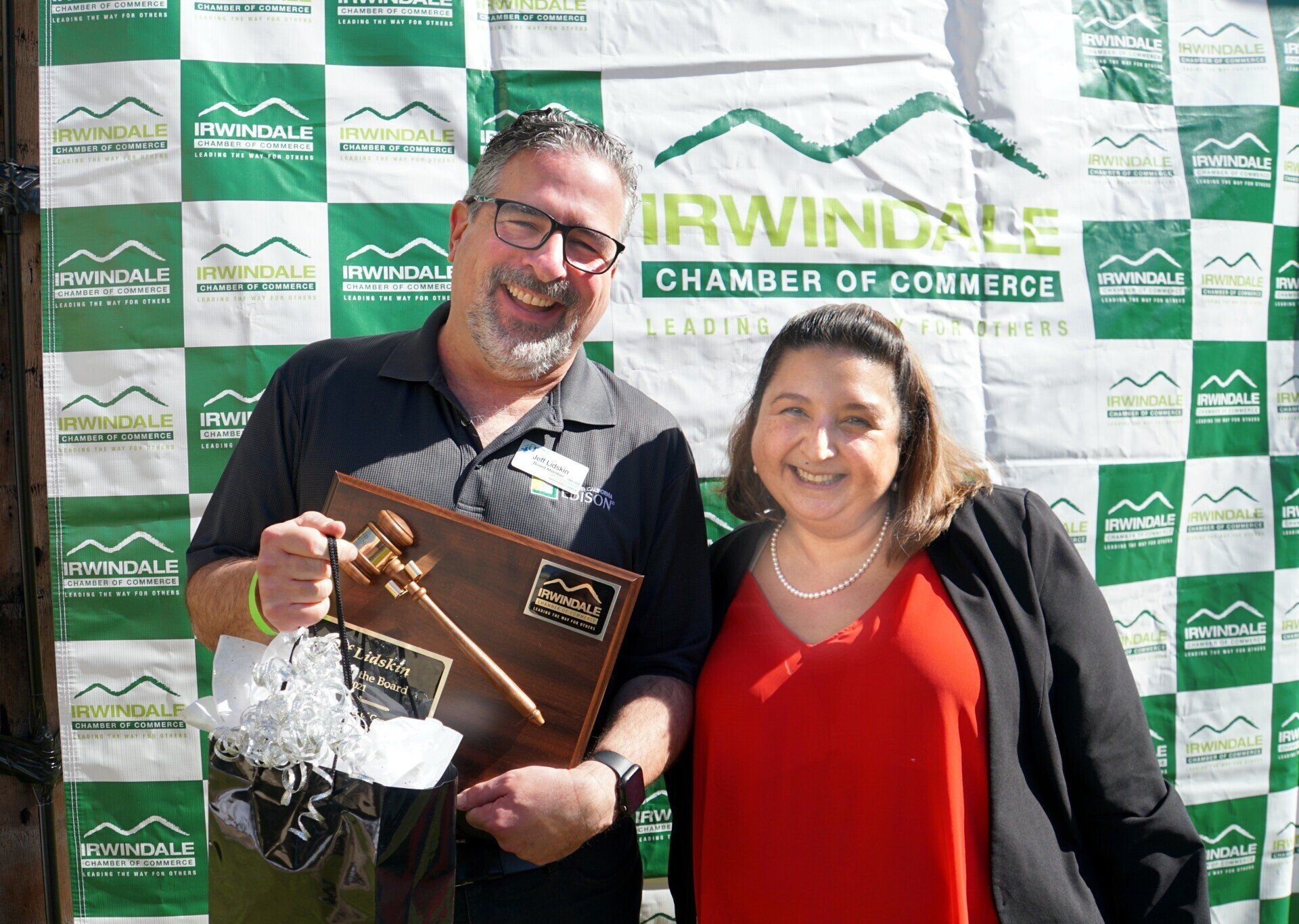 A man and a woman are standing next to each other holding a plaque.