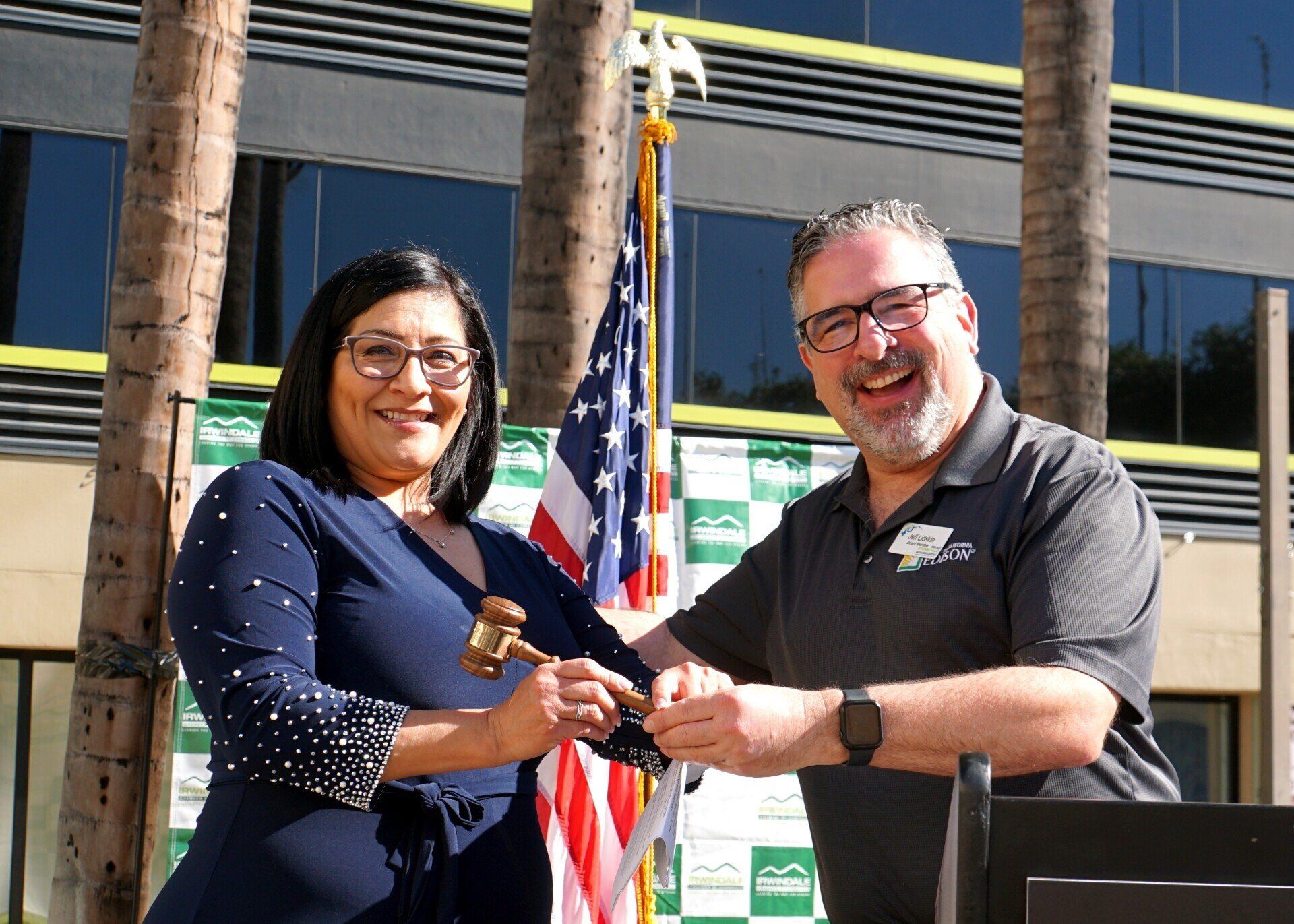 A man and a woman are standing next to each other in front of an american flag.