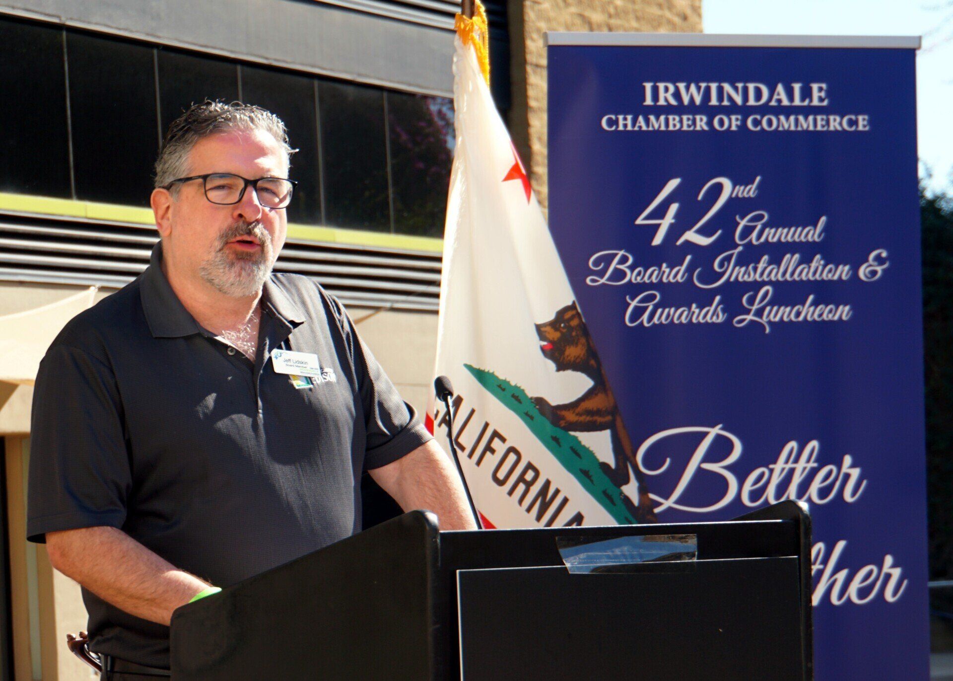 A man stands at a podium in front of a sign that says 42nd annual board installation & awards luncheon