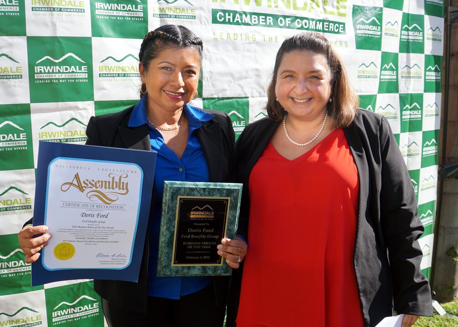Two women holding plaques and a certificate that says assembly