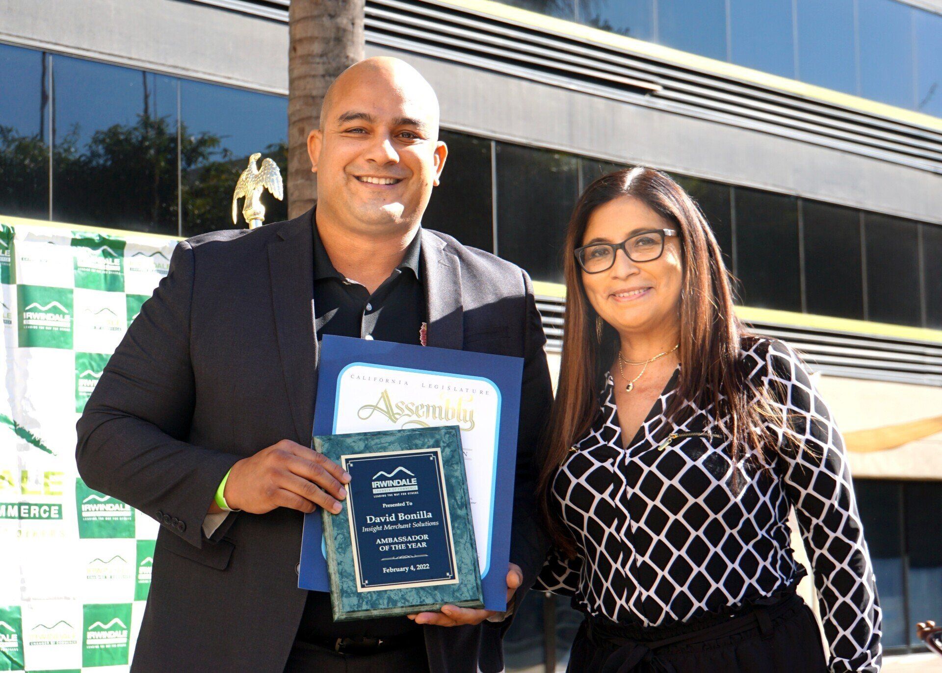 A man and a woman are standing next to each other holding plaques.