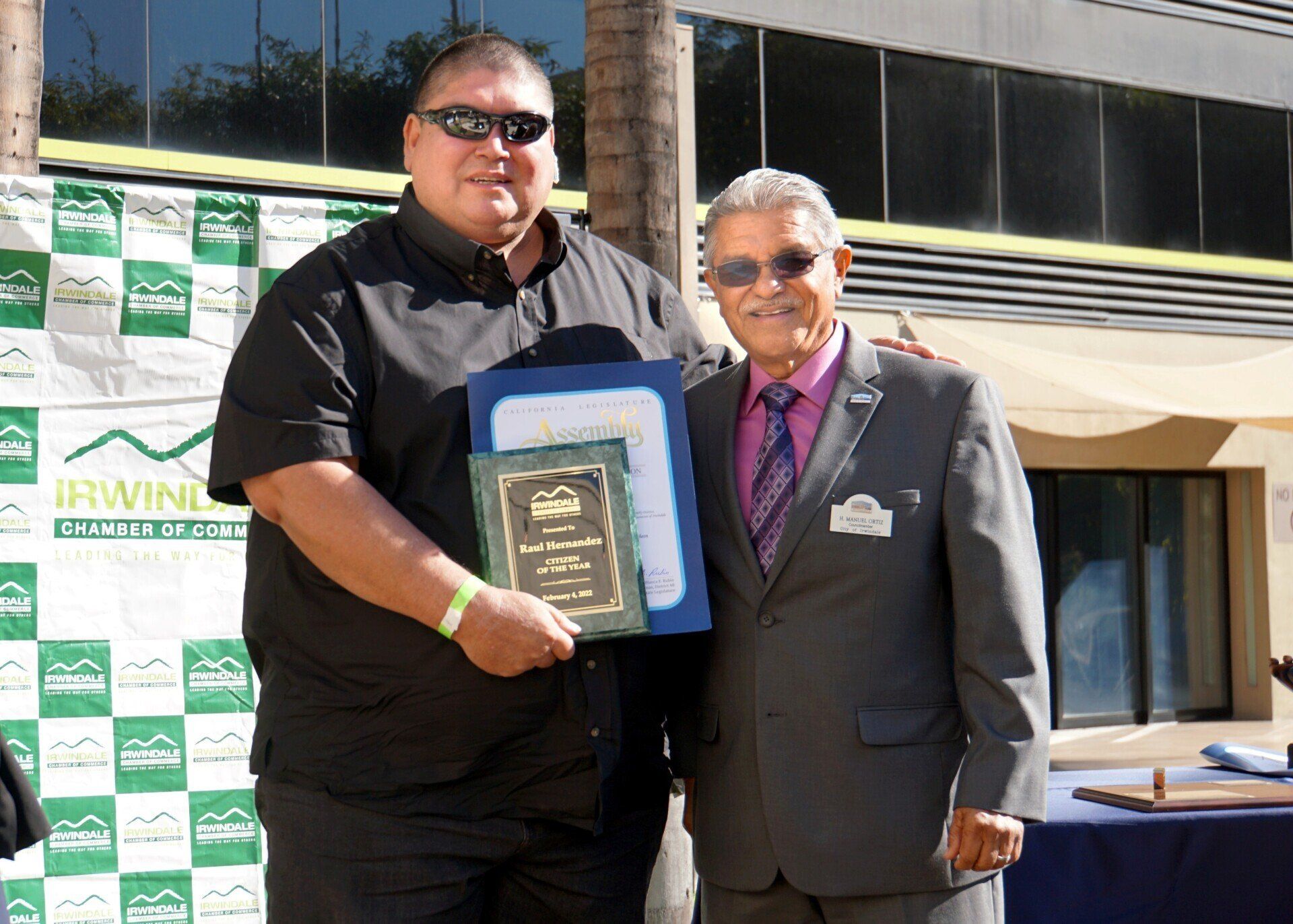 Two men are posing for a picture in front of a browning banner