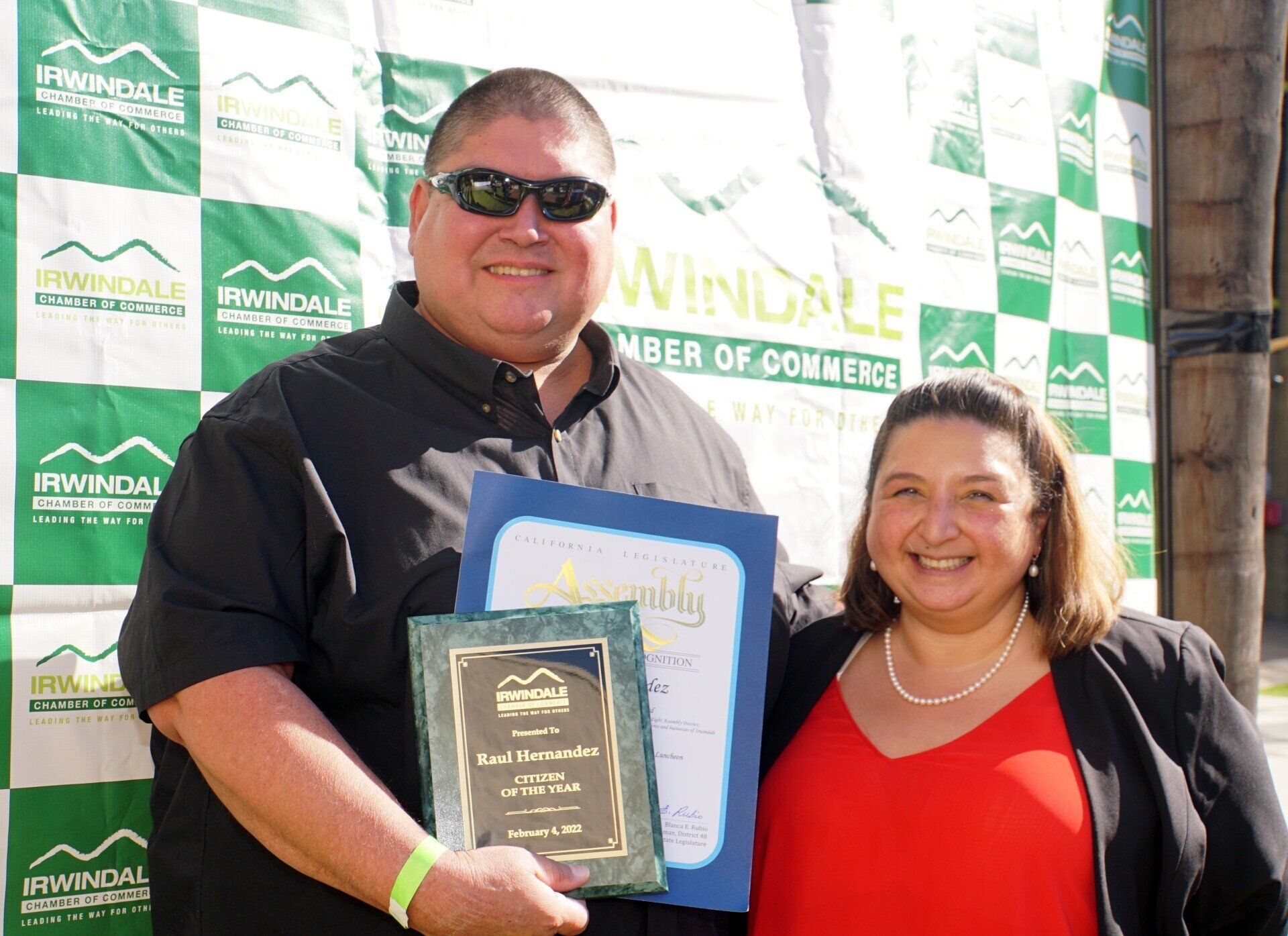 A man and woman are posing for a picture in front of a winddale banner