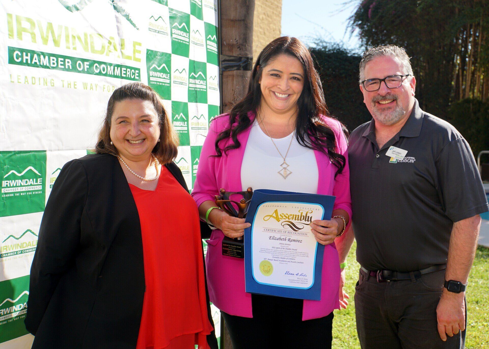 A woman is holding a certificate while standing next to two men.