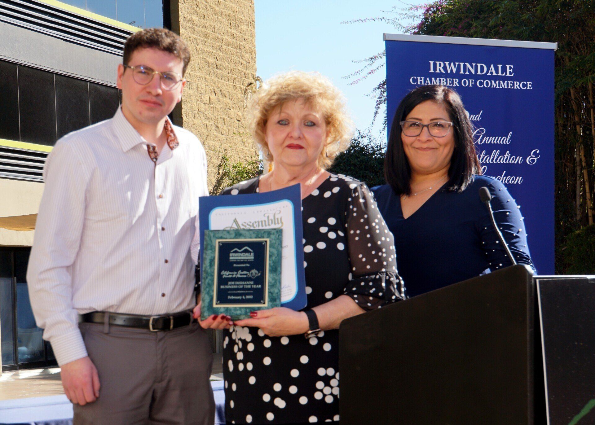 A man and two women standing in front of a sign that says irwindale chamber of commerce