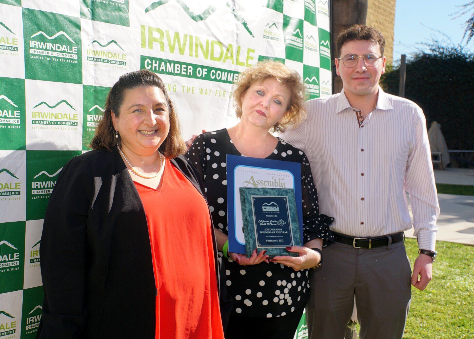 Three people are posing for a picture in front of a banner that says irwindale chamber of commerce