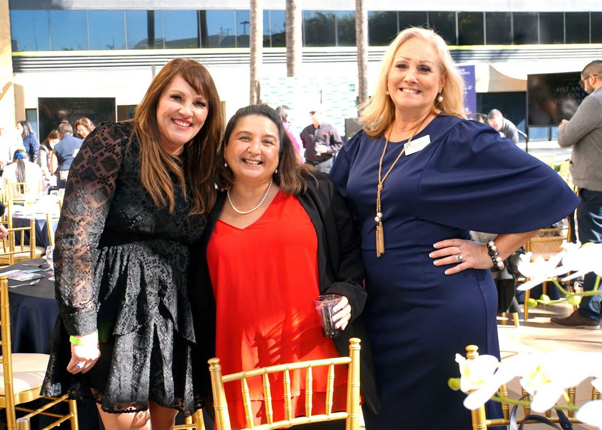 Three women are posing for a picture together at a party.