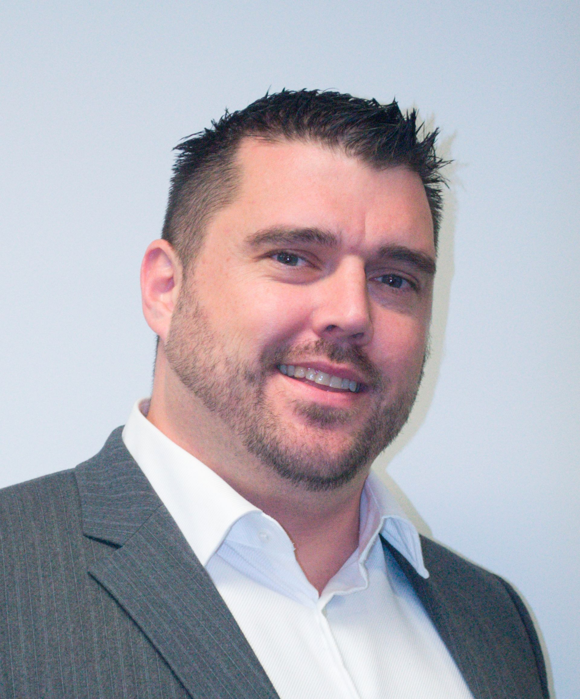 A man with a beard is wearing a suit and white shirt.