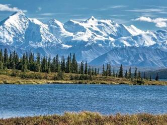 A lake with mountains in the background and trees on the shore.