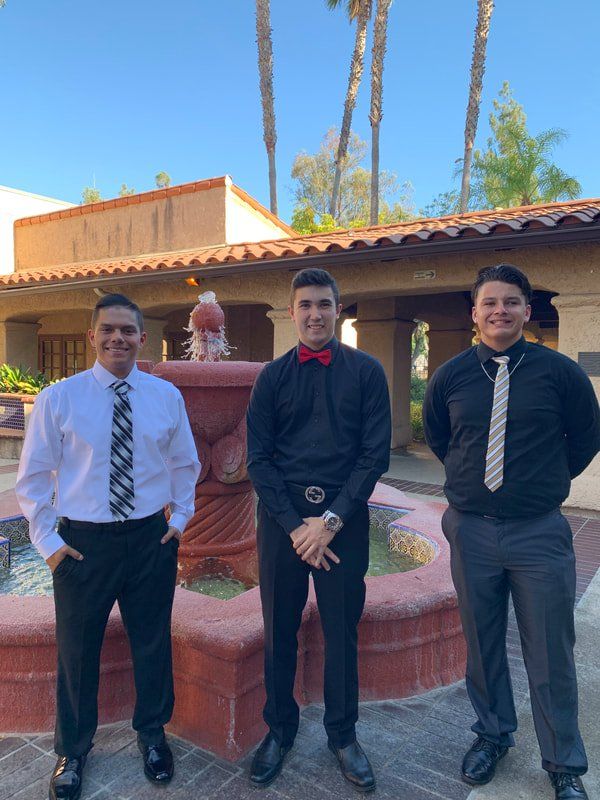 Three men are posing for a picture in front of a fountain