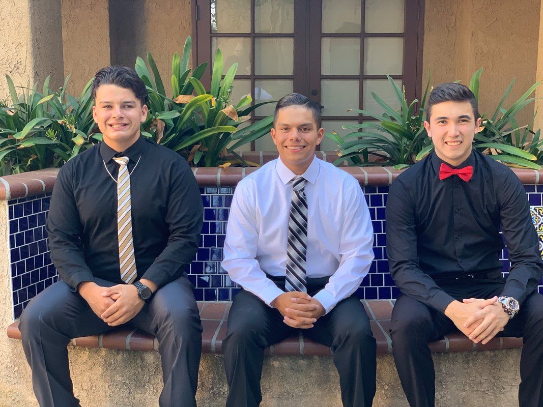 Three men in suits and ties are sitting on a bench.