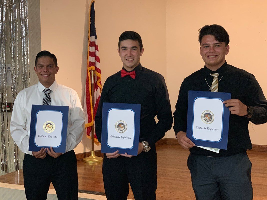 Three men are standing next to each other holding certificates in front of an american flag.