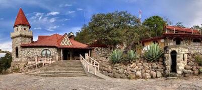 A large stone building with a red roof and stairs leading up to it.