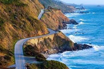 A road going down a cliff next to the ocean.