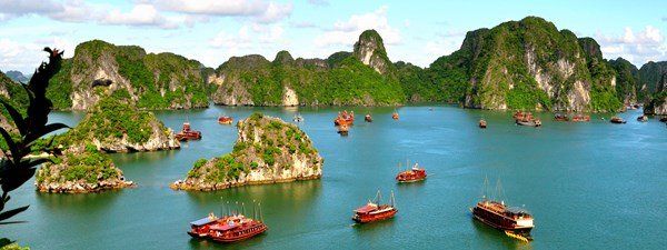 A group of boats are floating in a large body of water surrounded by mountains.