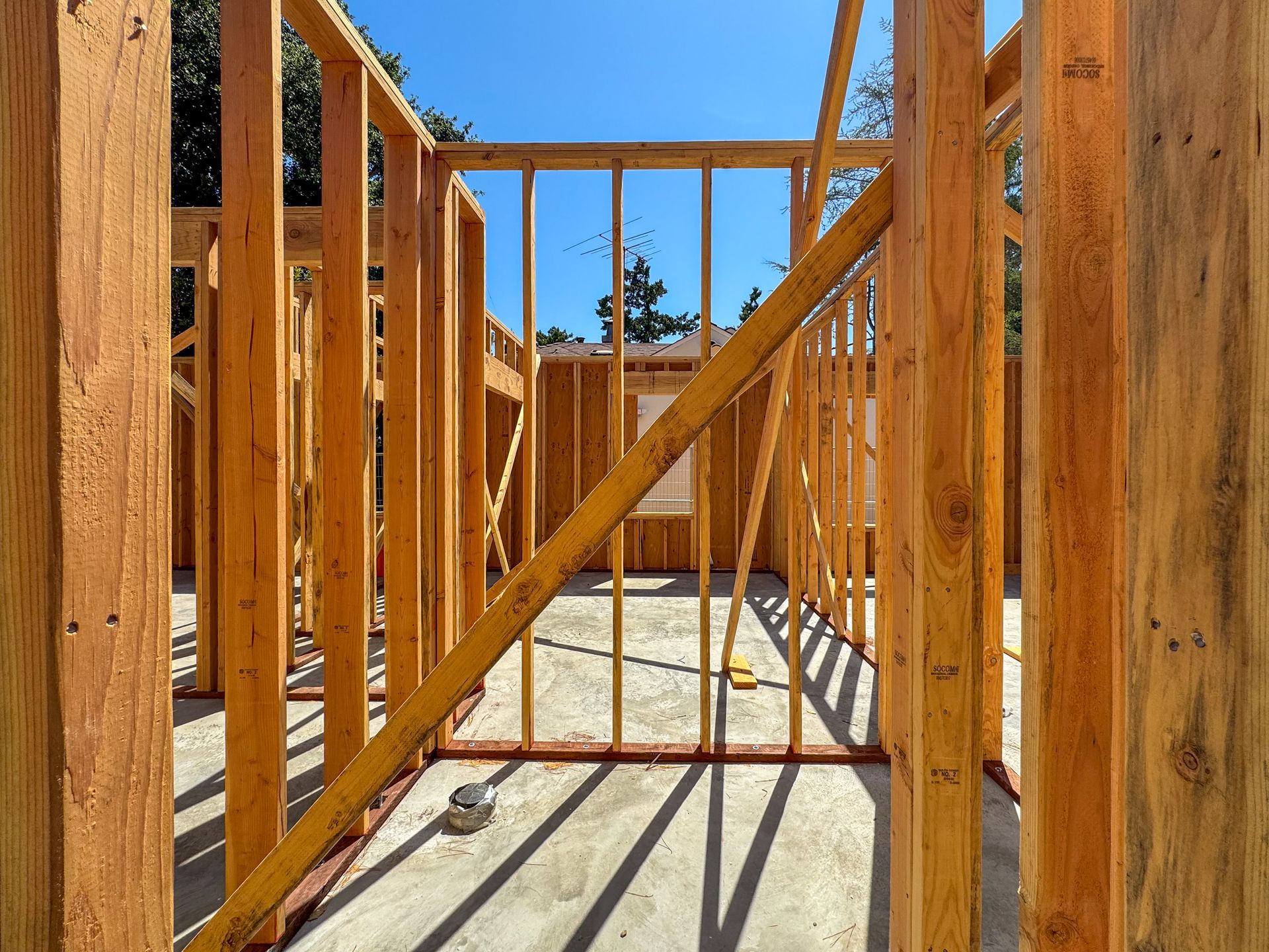 Interior view of a wooden house frame under construction against a blue sky.