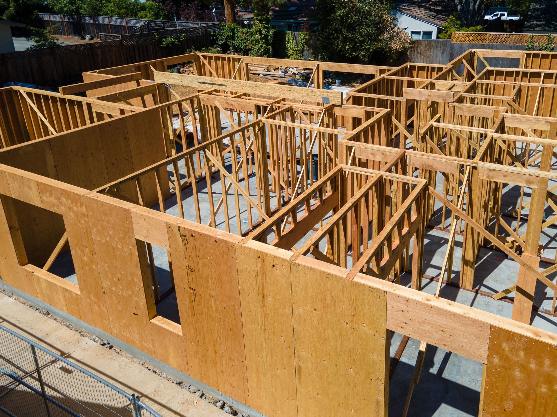 Wood frame of a house under construction with walls, windows, and roof supports.