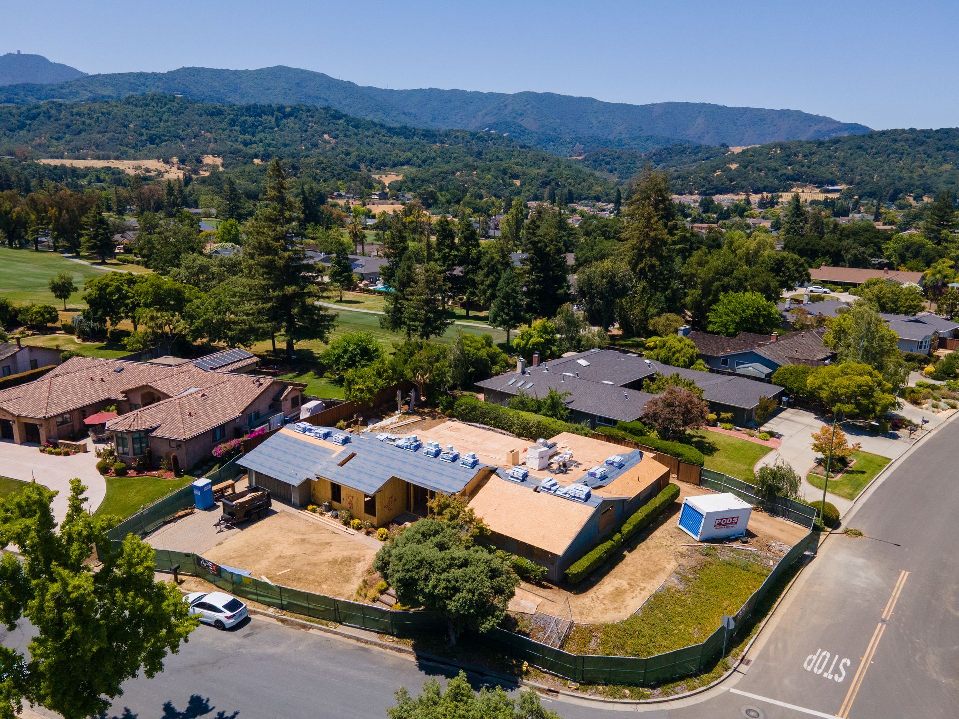 Aerial view of a house under construction in a suburban area with rolling hills in the background.