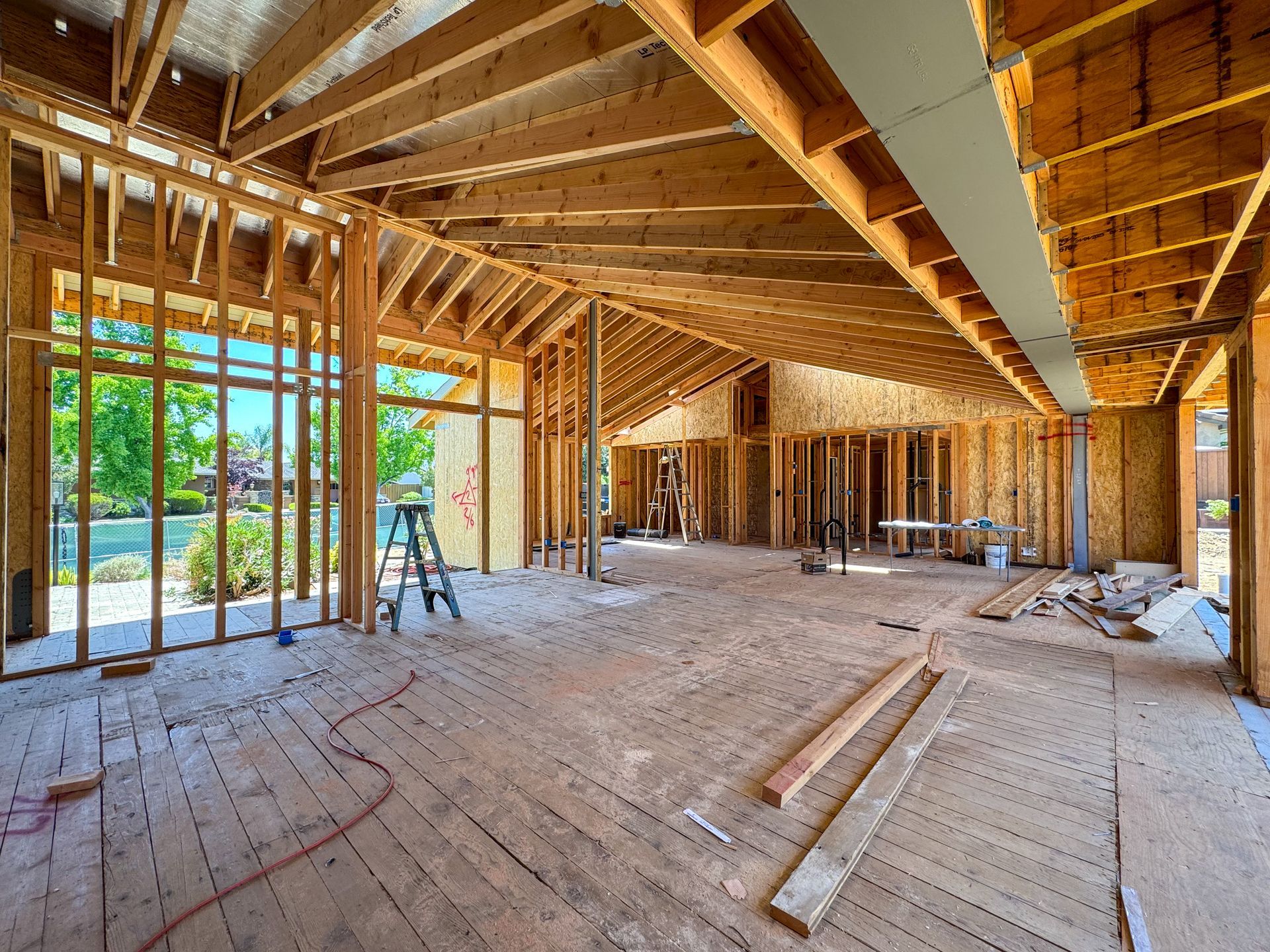 Interior framing of a home under construction, with wooden beams, exposed studs, and a view of a waterfront.