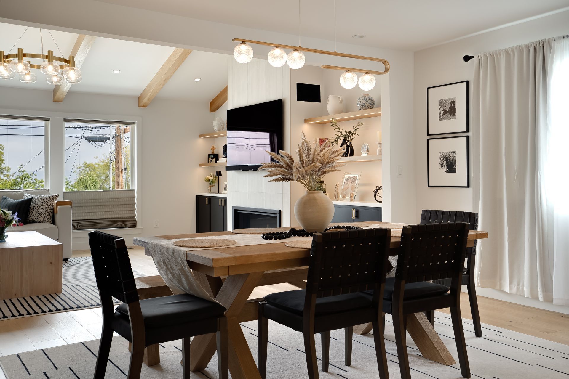 Dining room with wooden table and black chairs, lit shelves, and a window.