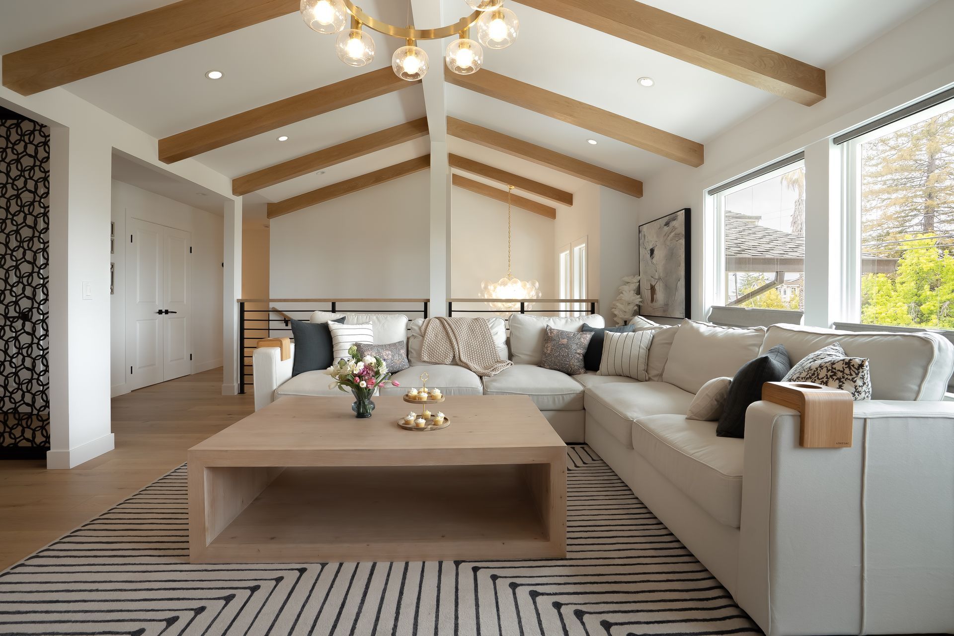 Living room with white sectional, wooden beams, and a modern rug.