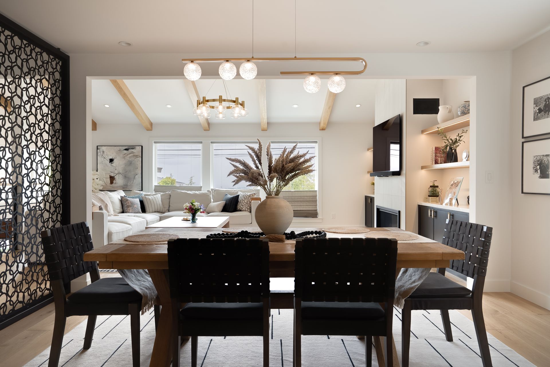 Dining room with table, black chairs, open to living room with couch, and decorative screen.