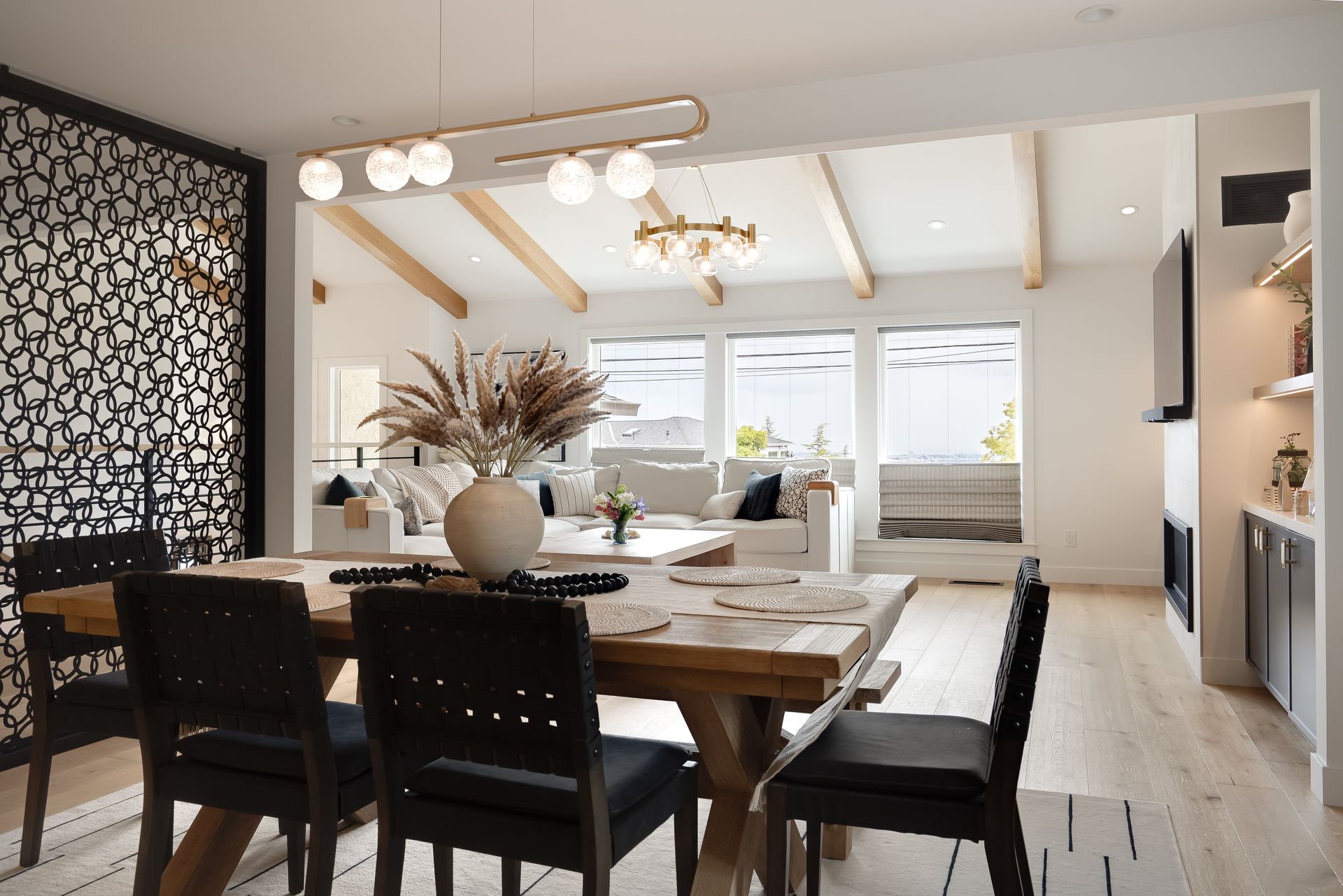 Dining room with a wooden table, black chairs, and a view of a living room with a white couch.
