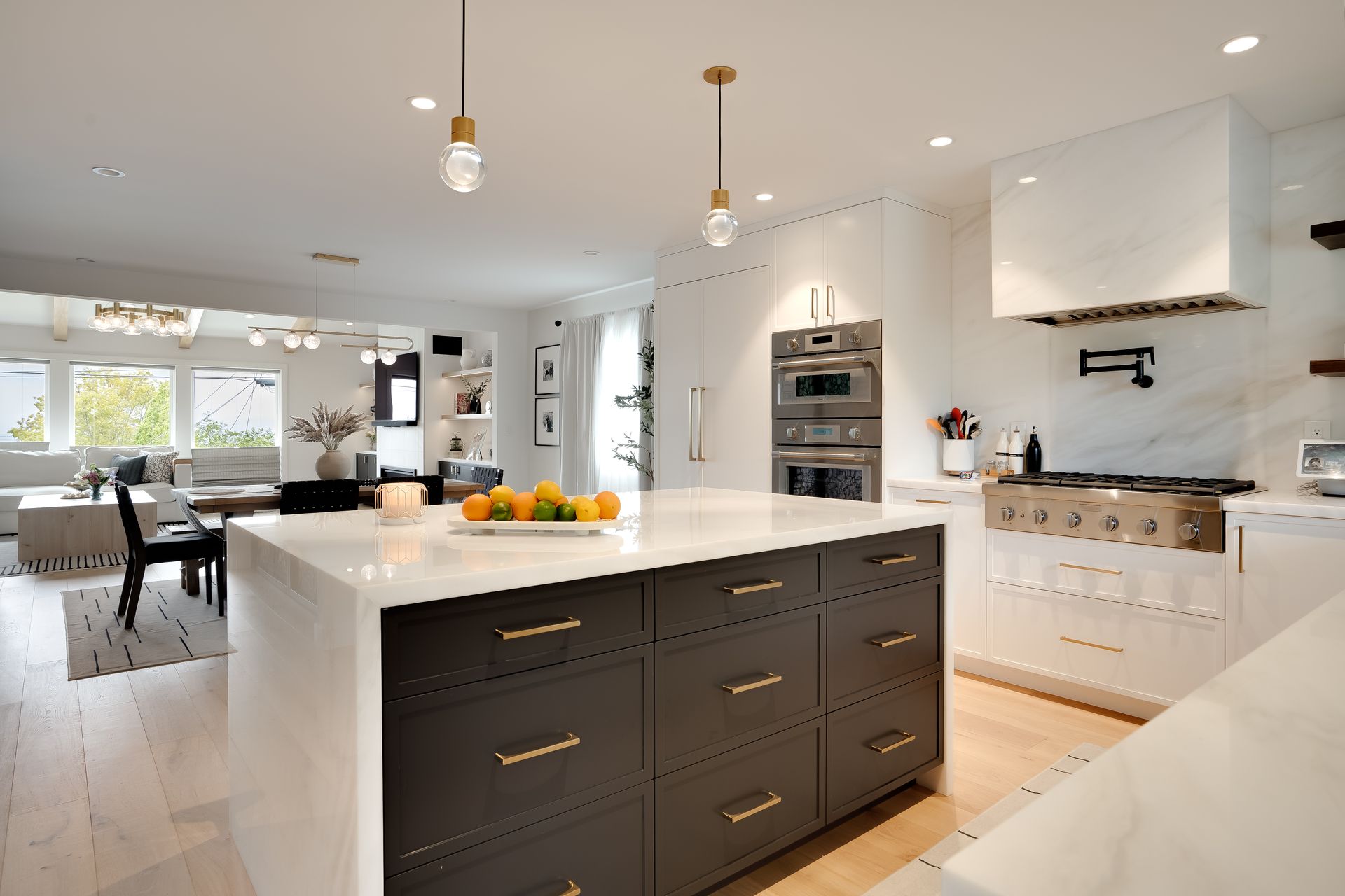 Modern kitchen with white and dark gray cabinets, marble countertops, and gold accents.