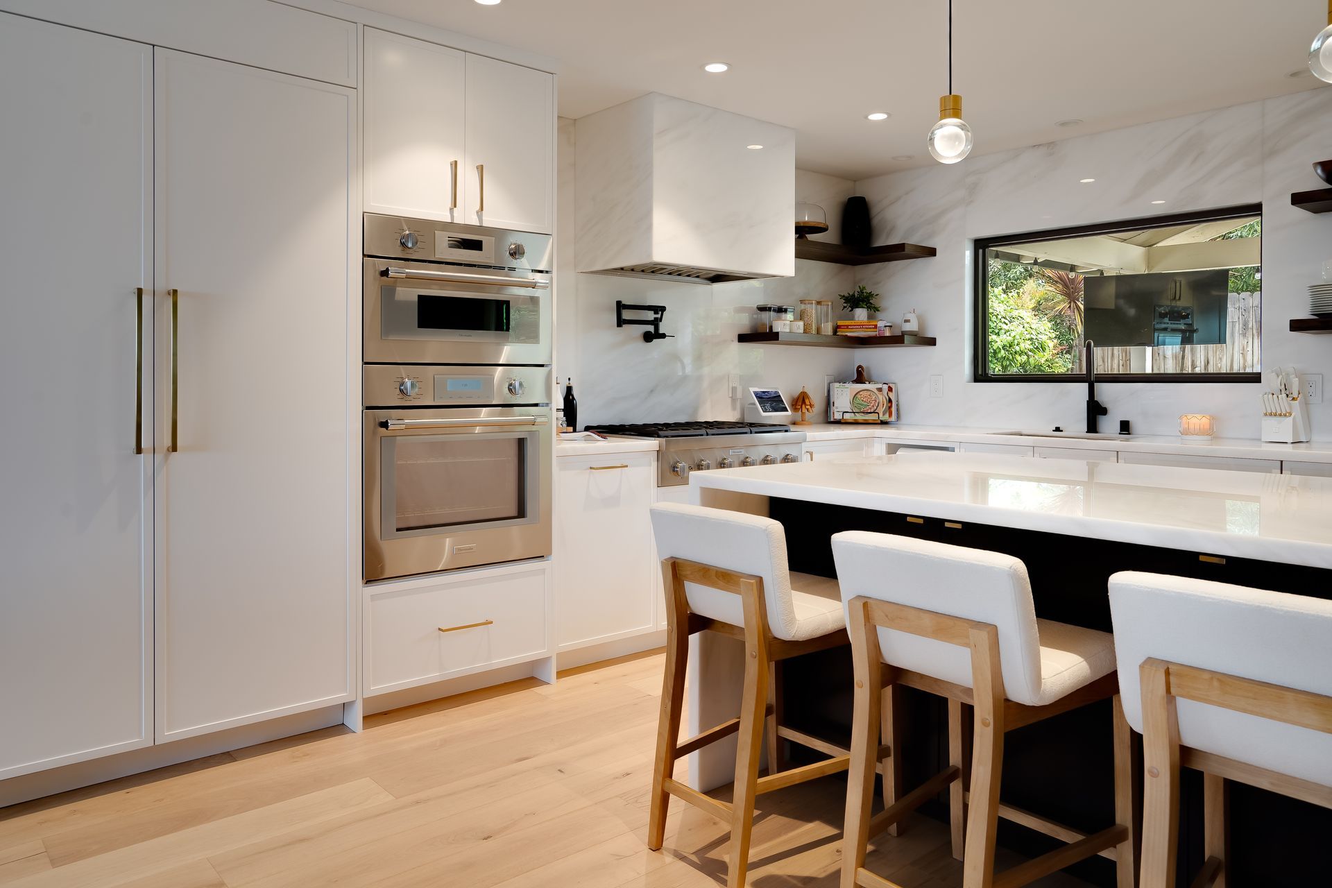 Modern kitchen with white cabinets, stainless steel appliances, and a marble island.