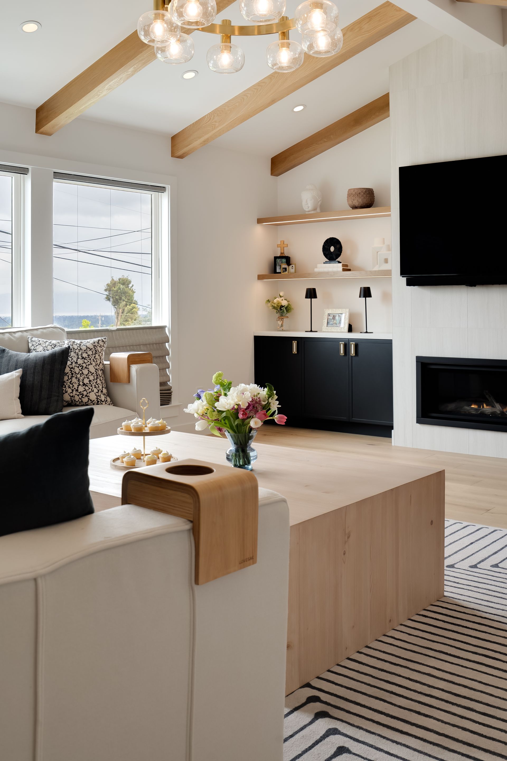 Modern living room with wood accents, fireplace, and built-in shelves with decor.