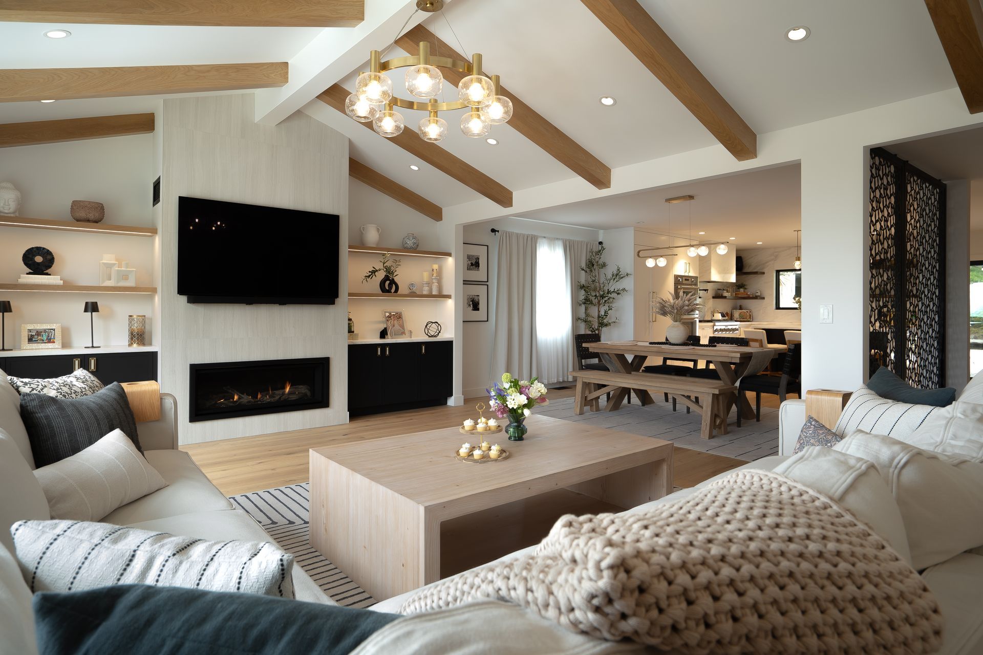 Living room with white walls, wood beams, fireplace, and neutral-toned furniture.