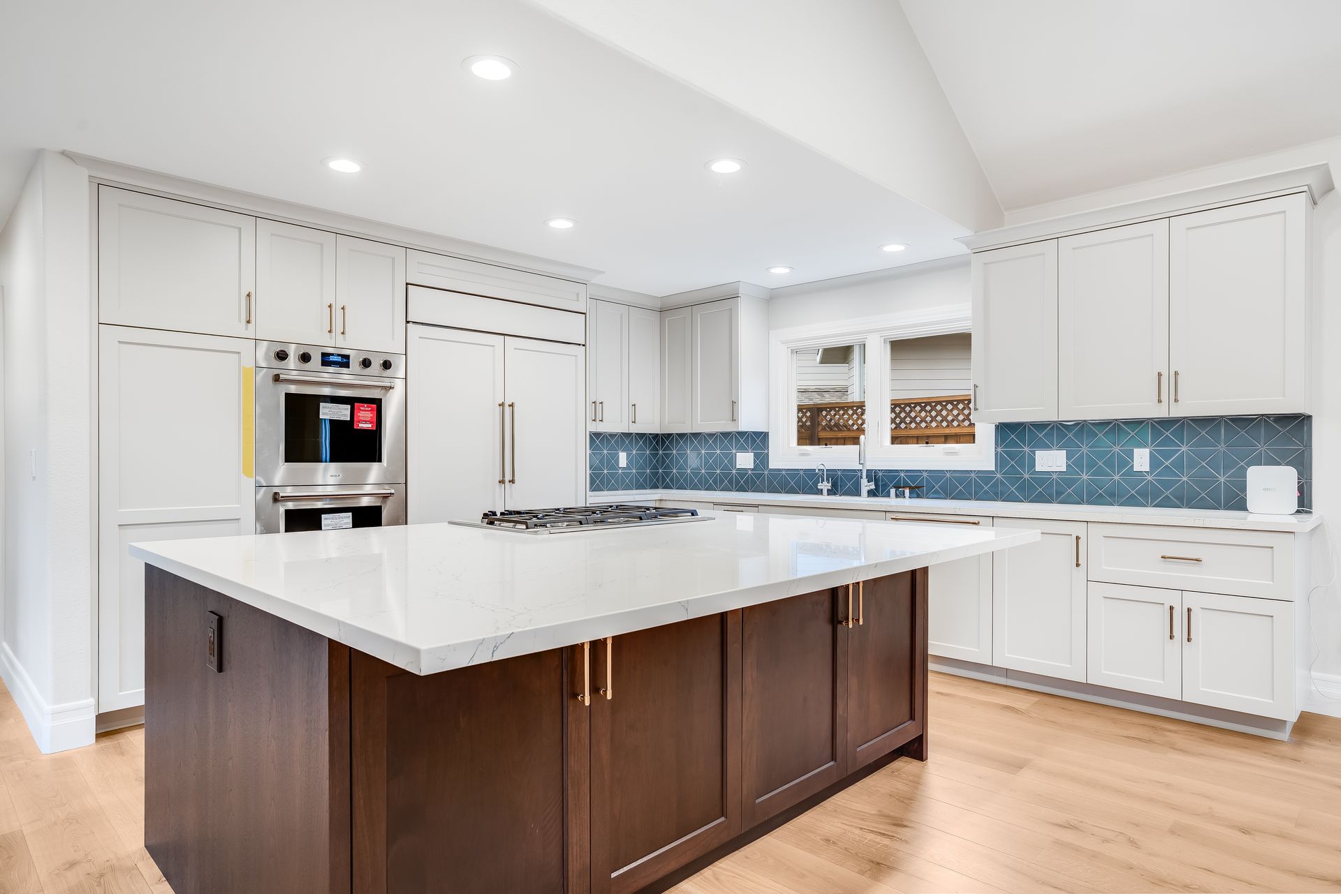Modern kitchen with white cabinets, a dark island, and blue backsplash.
