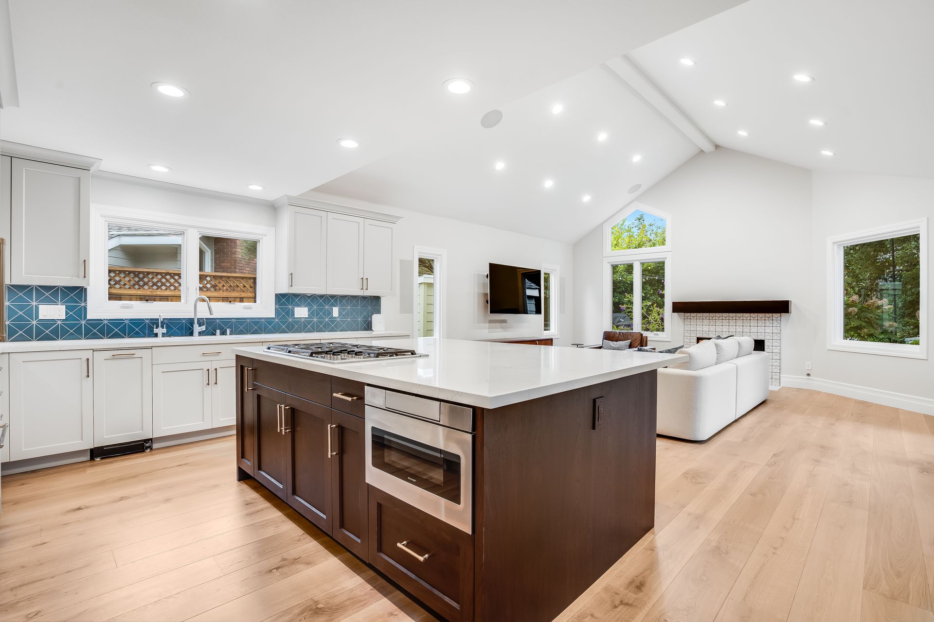 Bright kitchen with island, cabinets, and windows overlooking trees.