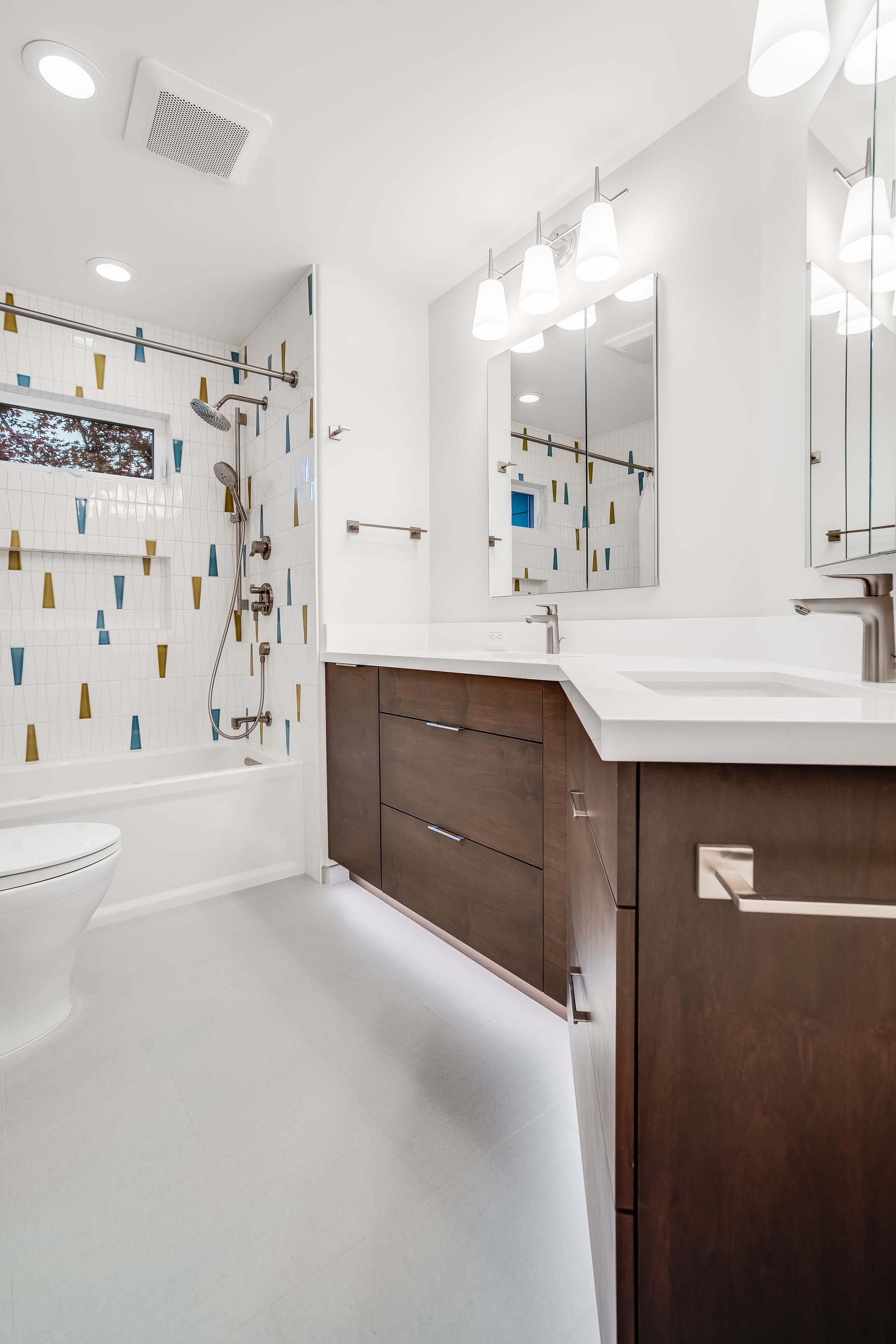 Modern bathroom with dark wood cabinets, white countertops, and patterned tile in the shower.