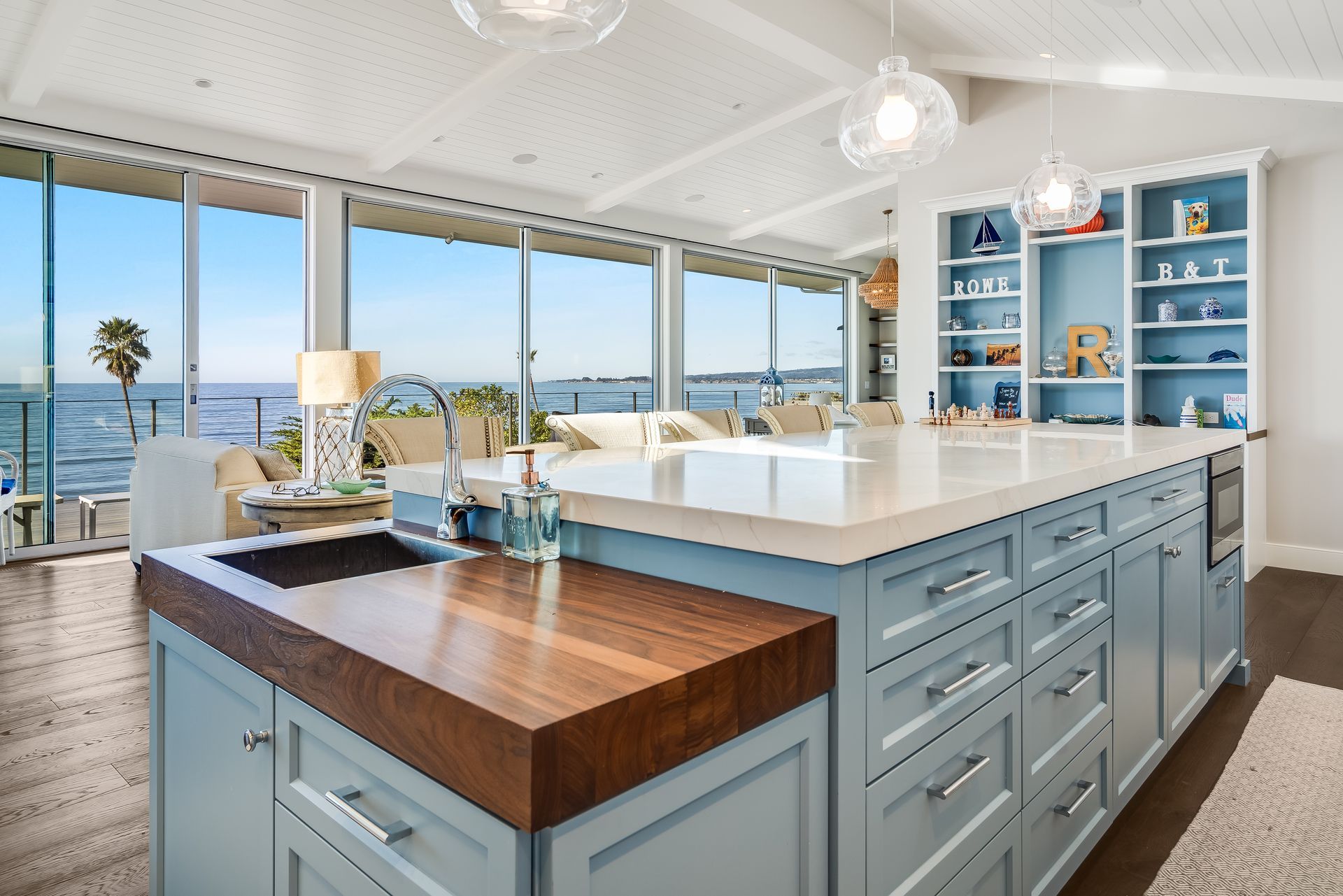 Coastal kitchen with a large island, water views, and blue cabinetry.