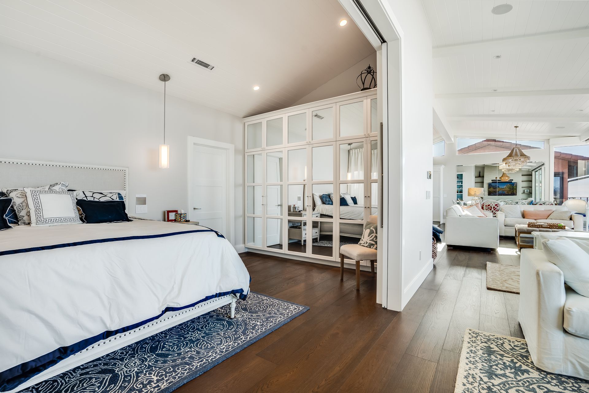 Bedroom with white walls, dark wood floor, a bed, and a sitting area.