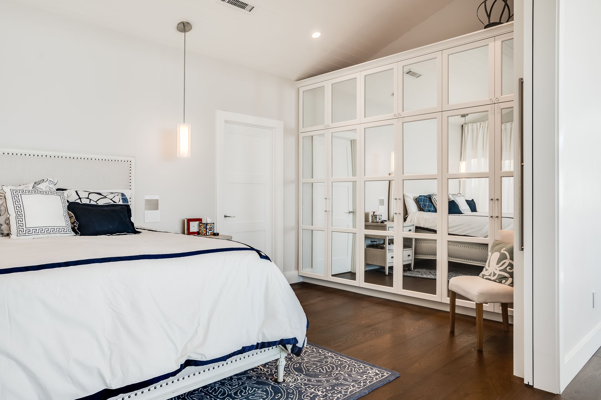 Bedroom with white walls, a bed with blue accents, and a mirrored closet.