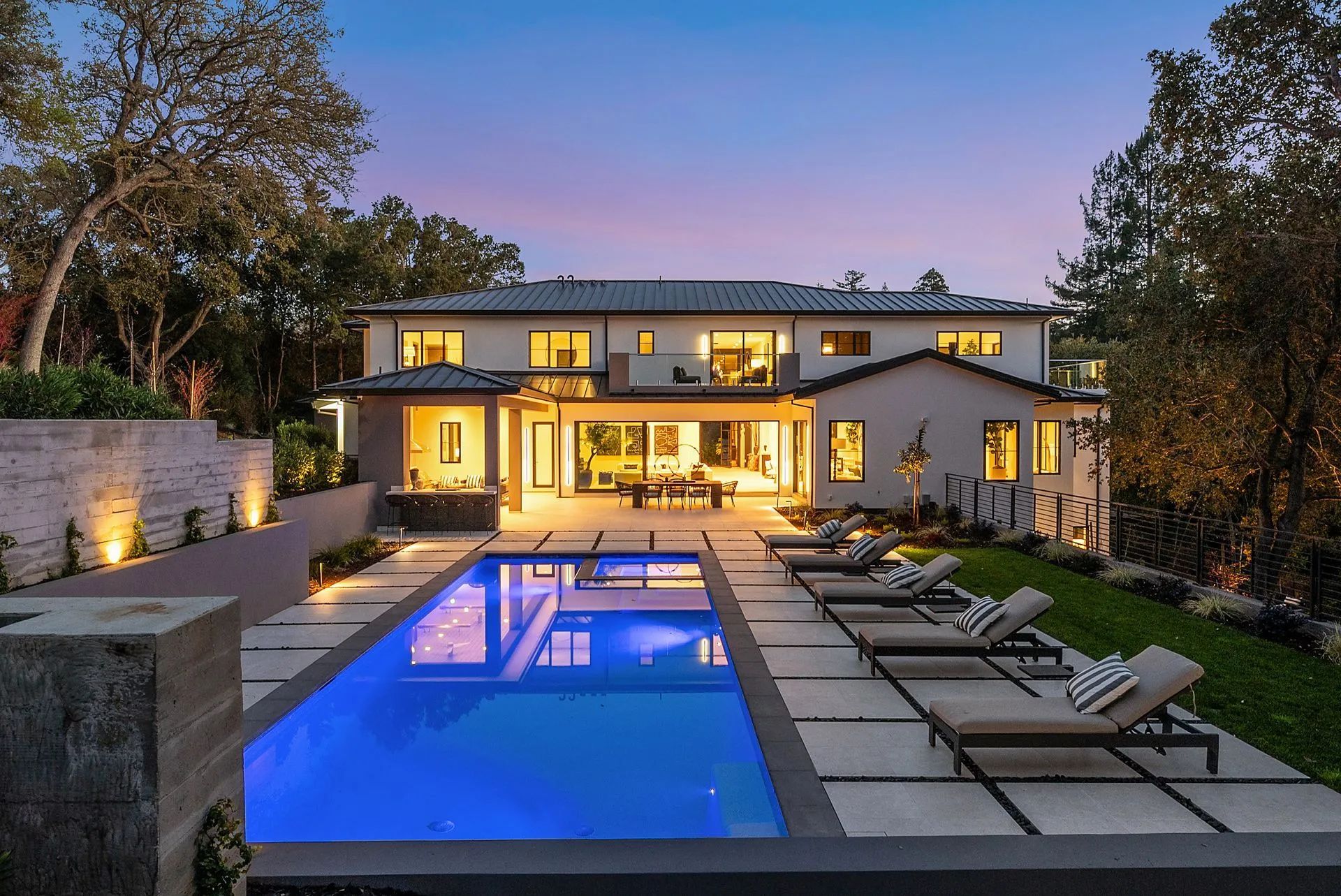 Luxurious home with pool, lounge chairs, and evening sky.