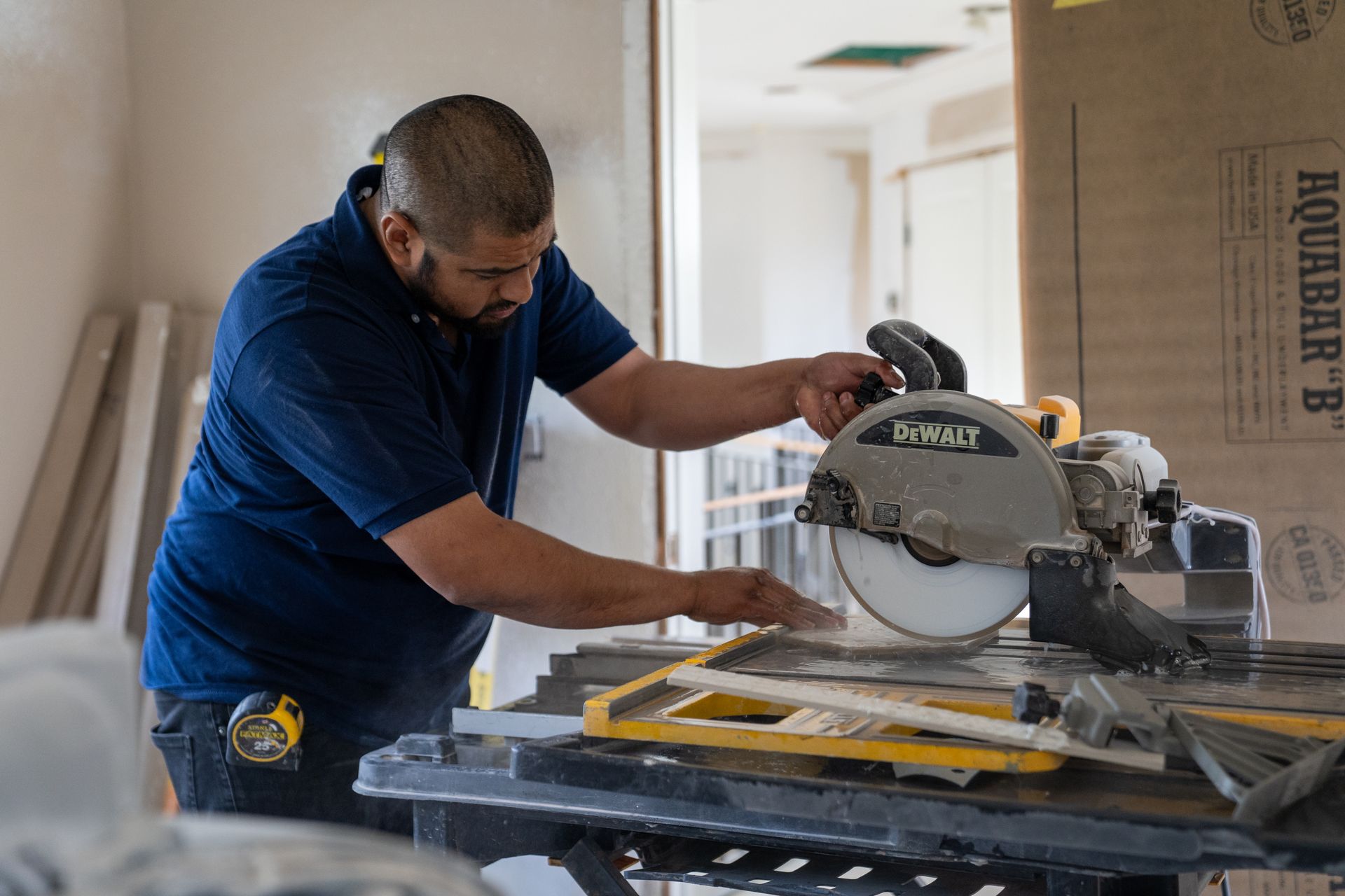 Man using a circular saw to cut tile in a room under construction.