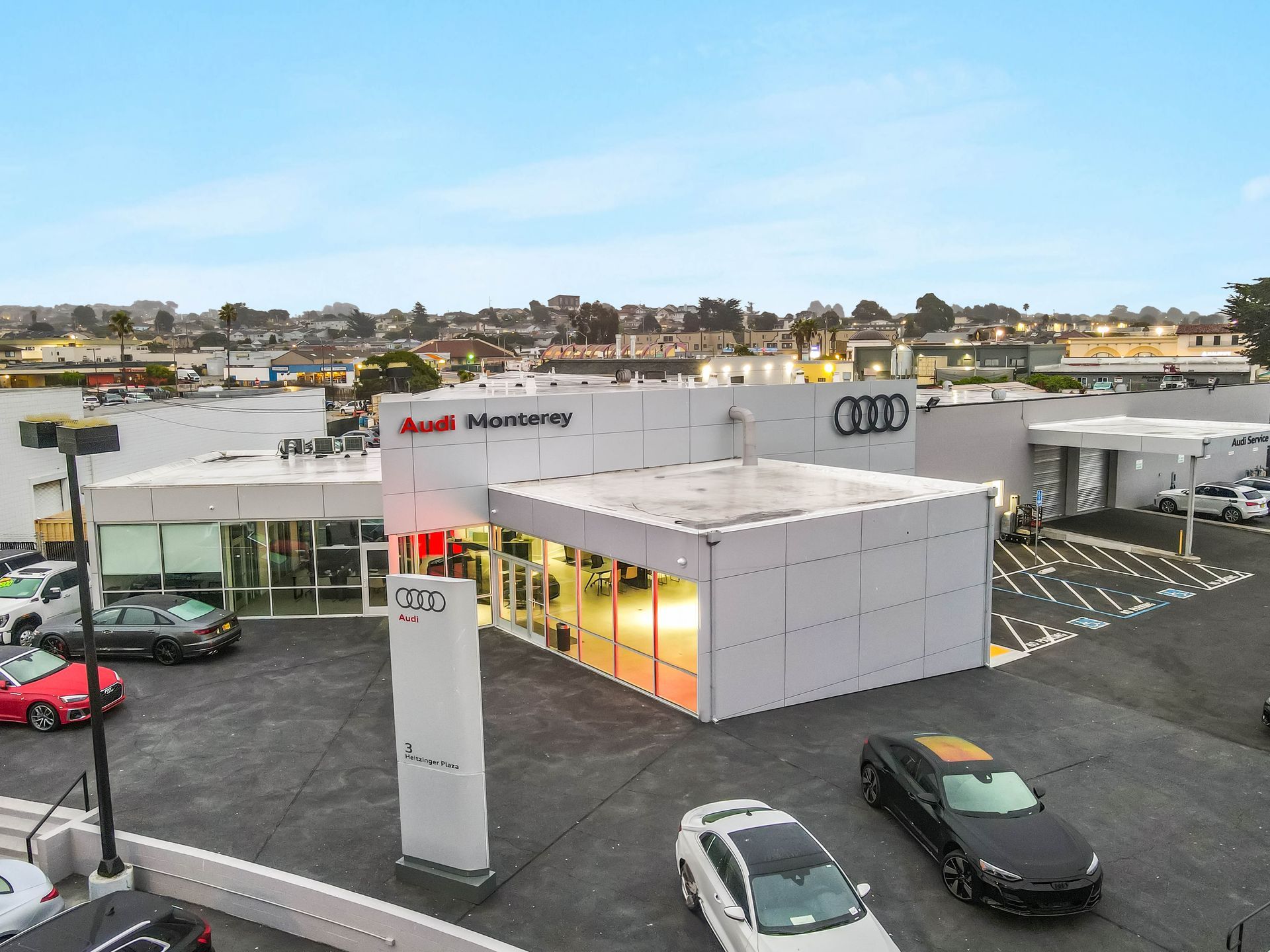 Audi dealership exterior with cars, modern architecture, and sign.