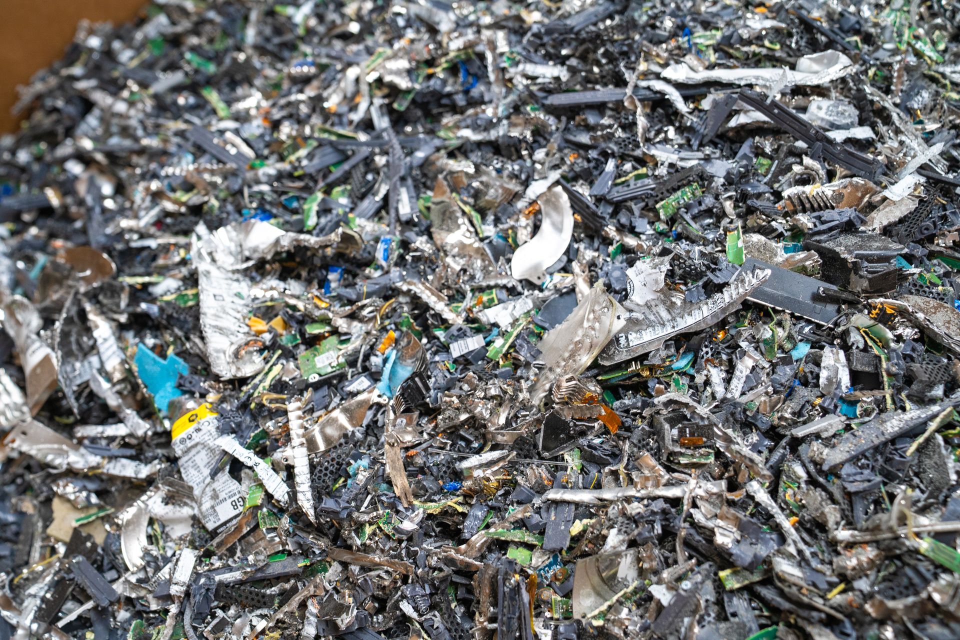 Shredded electronic waste: circuit boards, plastic, and metal, a pile of gray, black, and green debris.