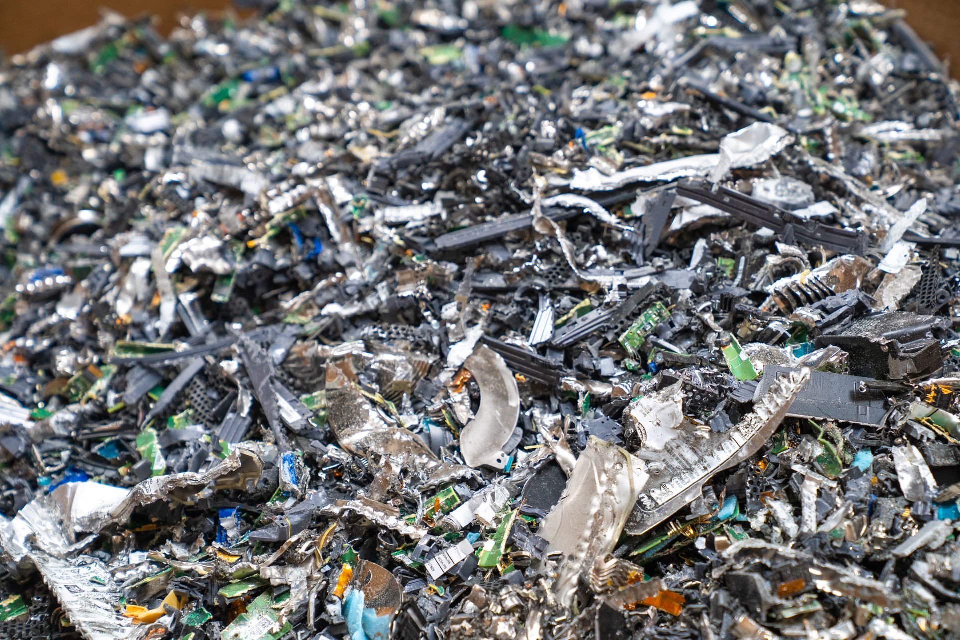 Pile of shredded electronic waste, including circuit boards and components, ready for recycling.