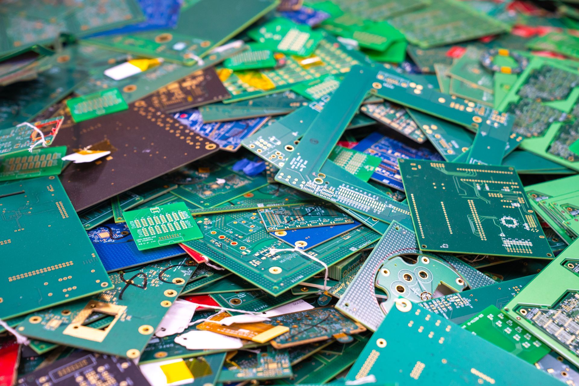 Pile of discarded circuit boards, mostly green, with various electronic components.