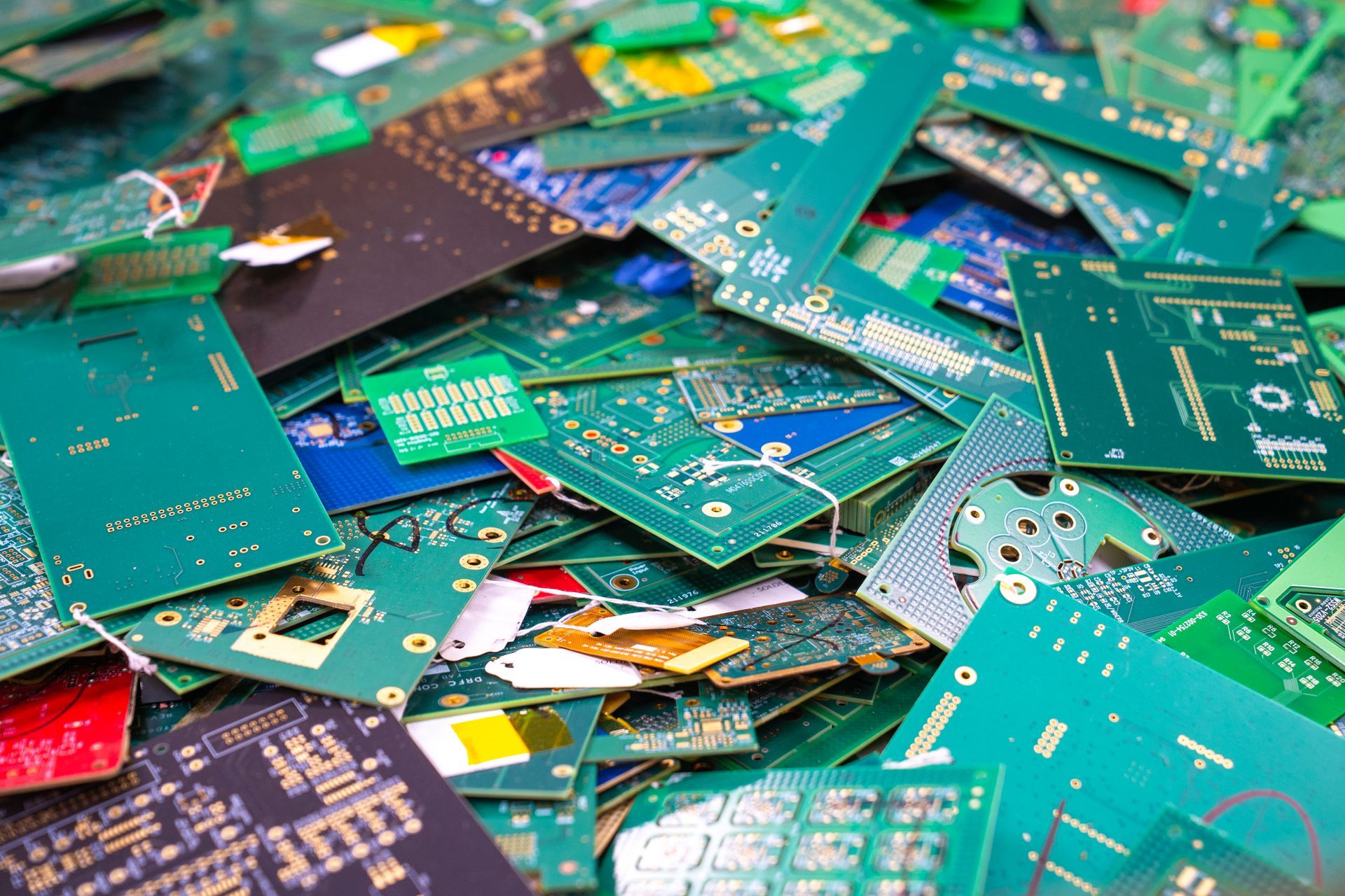 Pile of discarded circuit boards; green, blue, and gold electronic components.
