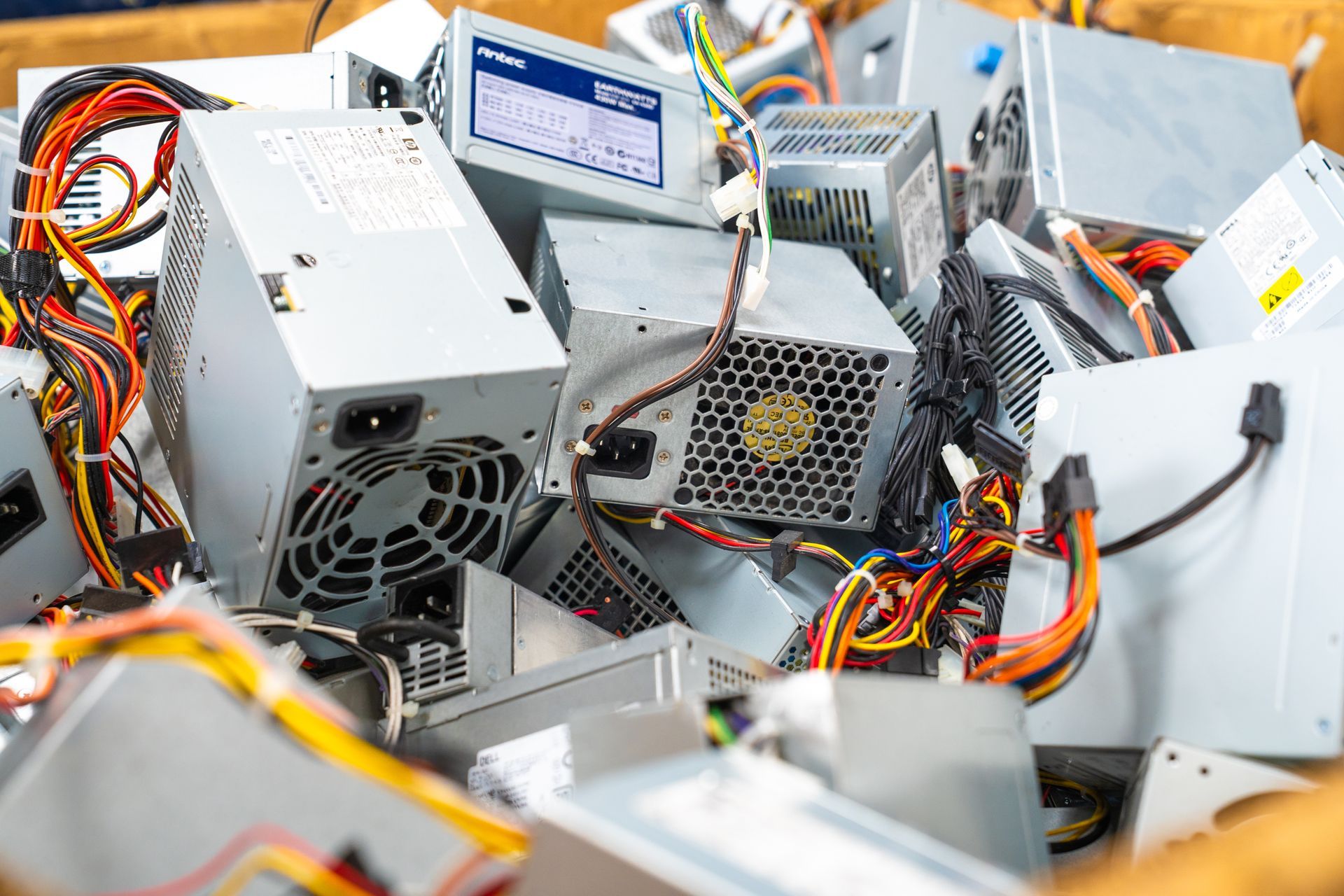 A bin overflowing with discarded computer power supply units; many have colorful wires.
