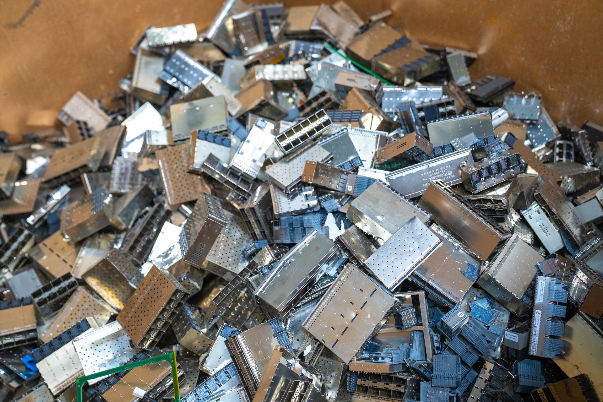 Pile of metal electronic components in a bin, likely for recycling.