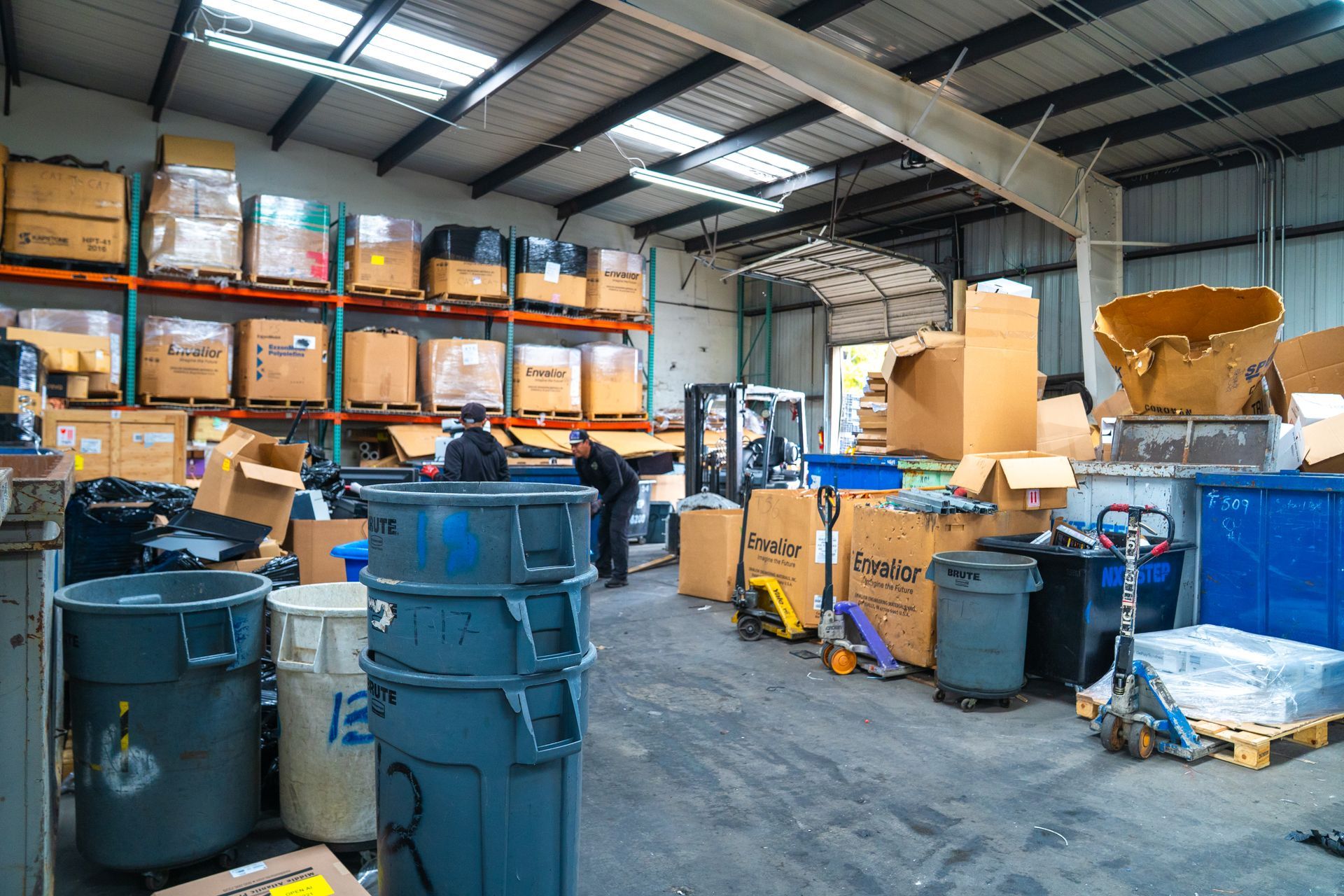 Warehouse interior with boxes, bins, and a person sorting items. Shelves in the background.